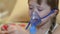 Girl ingaliruut inhaling steam treatment, sick child in hospital plays in phone.