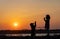 A girl in a jacket trains a guard dog of the Rottweiler breed against the backdrop of a lake and sunset