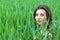 Girl in jeans clothes with beautiful hair lies on a green field with a dreamy look on her face.