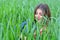 Girl in jeans clothes with beautiful hair lies on a green field with a dreamy look on her face.