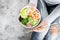 Girl in jeans holding shrimp poke bowl with seaweed, avocado, cucumber, radish, sesame seeds