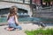 Girl in jeans sits near the fountain and feeding birds