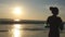 Girl jogging along ocean shore during sunrise. Silhouette of young woman running on sea beach at sunset. Female