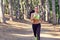 A girl jogging in the woods outdoors.