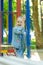 Girl joyfully and fervently laughs sitting on a hanging ladder in the playground