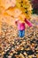 Girl jumping behind yellow autumn leaves