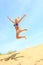 Girl jumping off a sand dune