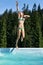 Girl jumping into the swimming pool in super hero pose