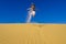 Girl jumping on the yellow sand dune