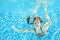 Girl jumps, dives and swims in pool underwater, happy active child has fun under water, kid sport