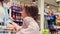 Girl jumps and pulls mom hand ask her to buy sweets in the store and shows her the sweet department, they must go there.