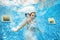 Girl jumps and swims in pool underwater, child has fun in water