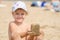 Girl keeps hands on turret of sand sitting on a river beach