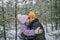 Girl kisses mom with happiness that the first long-awaited snow has fallen, family walks in forest