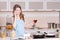 Girl in the kitchen with glass of red wine on phone