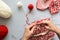 Girl knits red and white jacquard hat knitting needles on gray wooden background. Process of knitting.