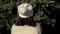 Girl in a knitted white hat admires a fluffy green spruce. Back view.