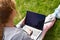 Girl with laptop on green grass. Remote schooling. The child works at the computer