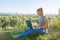 A girl with a laptop in nature, against the forest and the sky with sunlight. The concept of combining leisure and work