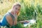 A girl with a laptop in nature lying on the grass with sunlight. The concept of combining leisure and work. Individual