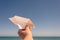 A girl is launching a paper airplane on the sunset beach. Travel and summer concept.