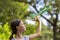 Girl launching toy airplane against green garden and sky, evening lighting.