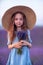 Girl lavender field in a blue dress with flowing hair in a hat stands in a lilac lavender field