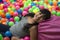 Girl lays on the big heap of multicolored small balls.