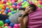 Girl lays on the big heap of multicolored small balls.