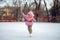 Girl learns to skate on an ice rink on a street in winter