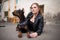 A girl in leather, with a Doberman, in an old yard.