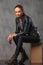 Girl in leather jacket posing in studio seated resting