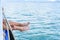 Girl legs hang off edge Passenger boat in ocean.