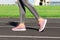 Girl legs in pink sport shoes standing on a running track with stadium stands. Sports and healthy concept