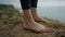 Girl legs standing hilltop closeup. Unknown barefoot woman relaxing on sea beach