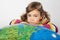 Girl lies on big inflatable globe, chin on hands