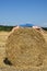 The girl lies on her back on a large round haystack on a mowed field