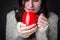 Girl in a light sweater holding red cup of coffee