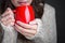 Girl in a light sweater holding red cup of coffee