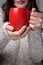 Girl in a light sweater holding a red cup of coffee