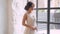 Girl in a light white luxurious wedding dress poses, stands alone in a spacious room, the interior is in a Scandinavian