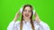 Girl listens to music on headphones . Green screen