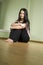 A girl with long black hair sitting on the floor