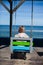 A girl with long blonde hair is sitting on a swing with a view of the sea, photo from the back