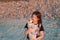 A girl with long curly hair on the beach with a puppy in her arms at sunset