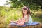 A girl with long dark hair sits barefoot on a haystack in summer and plays with a doll