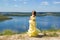 A girl in a long dress dancing on a cliff by the bay