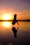 girl in a long dress on a salty pink lake against the background of a bright sunset. dark silhouette in flight