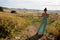 Girl in long green dress in the village at the fence in the morning