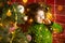 A girl with long hair and garlands lies on a red plaid under a Christmas tree with toys in a warm knitted sweater. Christmas, New